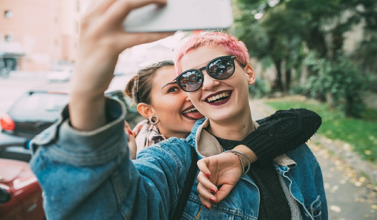 Smiling young women taking selfie with smartphone outdoors