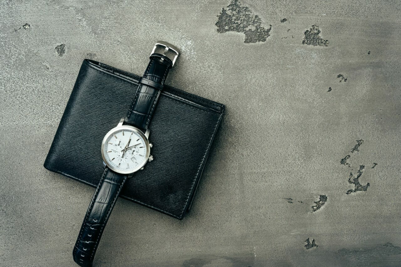 male-watch-and-leather-wallet-on-dark-grey-surface-close-up