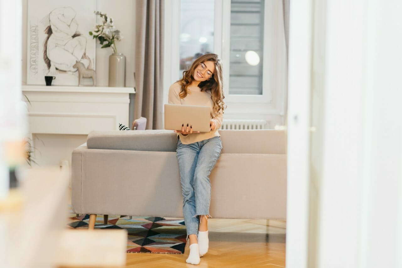 romantic-female-student-in-white-socks-holding-laptop-and-smiling