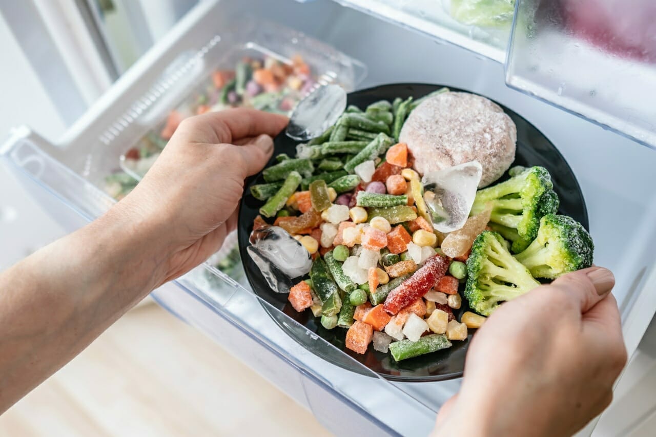 hands-are-taking-plate-frozen-food-out-freezer-fridge