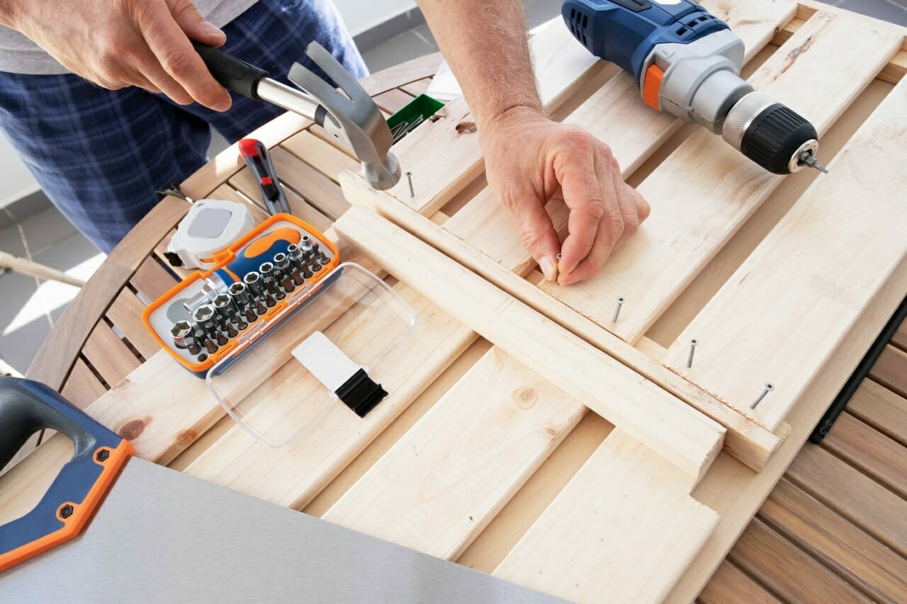 hands-driving-nail-with-hammer-into-wooden-shelf