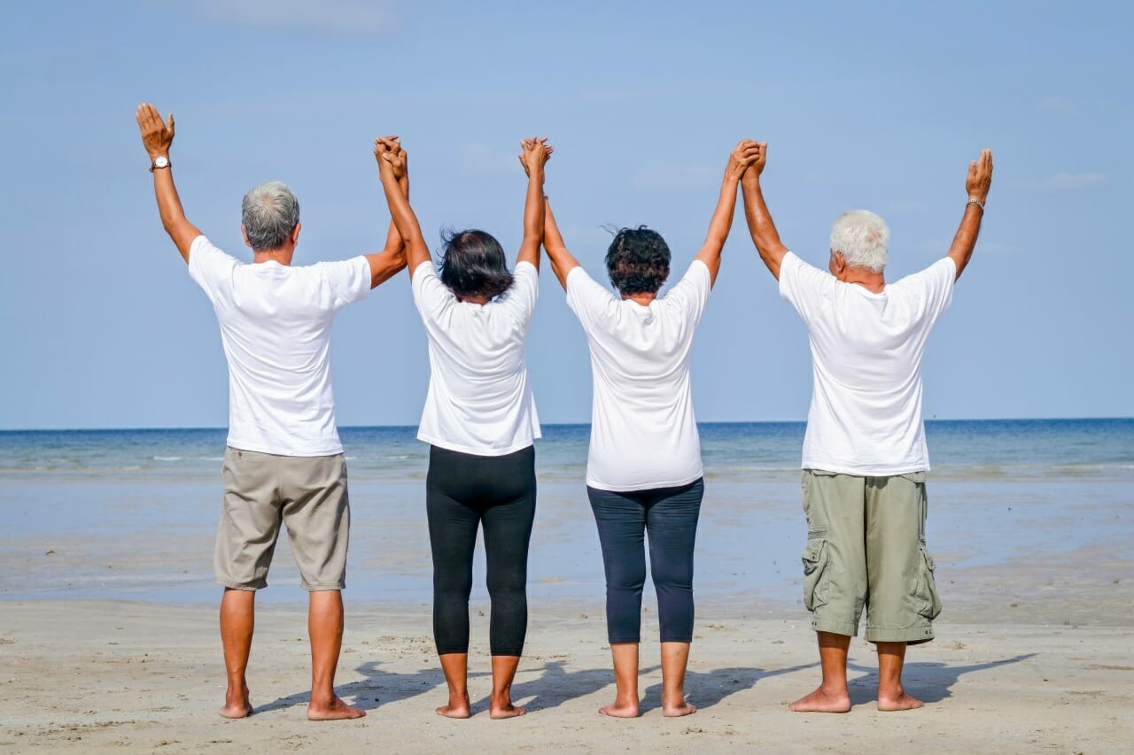 happy-group-of-elderly-friends-come-to-rest-at-the-sea-standing-holding-hands-and-facing-the-sea