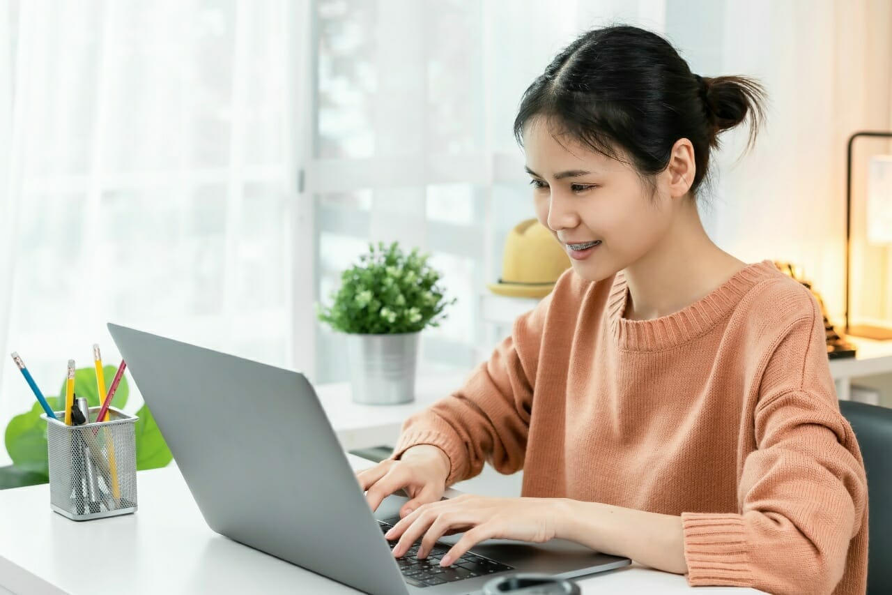 smiley-asian-young-woman-using-a-laptop-at-the-table