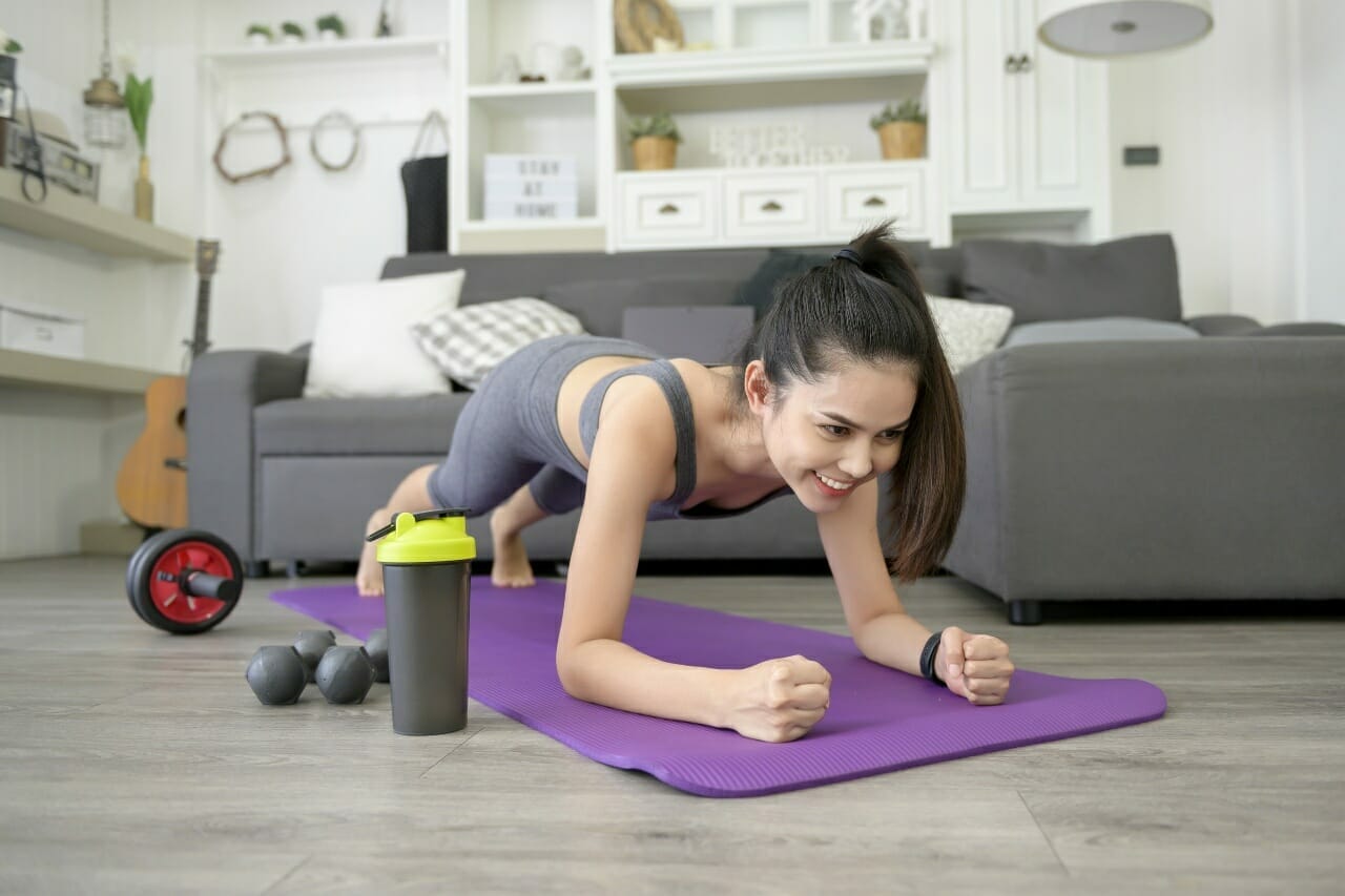 woman-is-doing-yoga-plank-watching-online-training-tutorials-her-laptop-living-room-fitness-workout-home-health-care-technology-concept