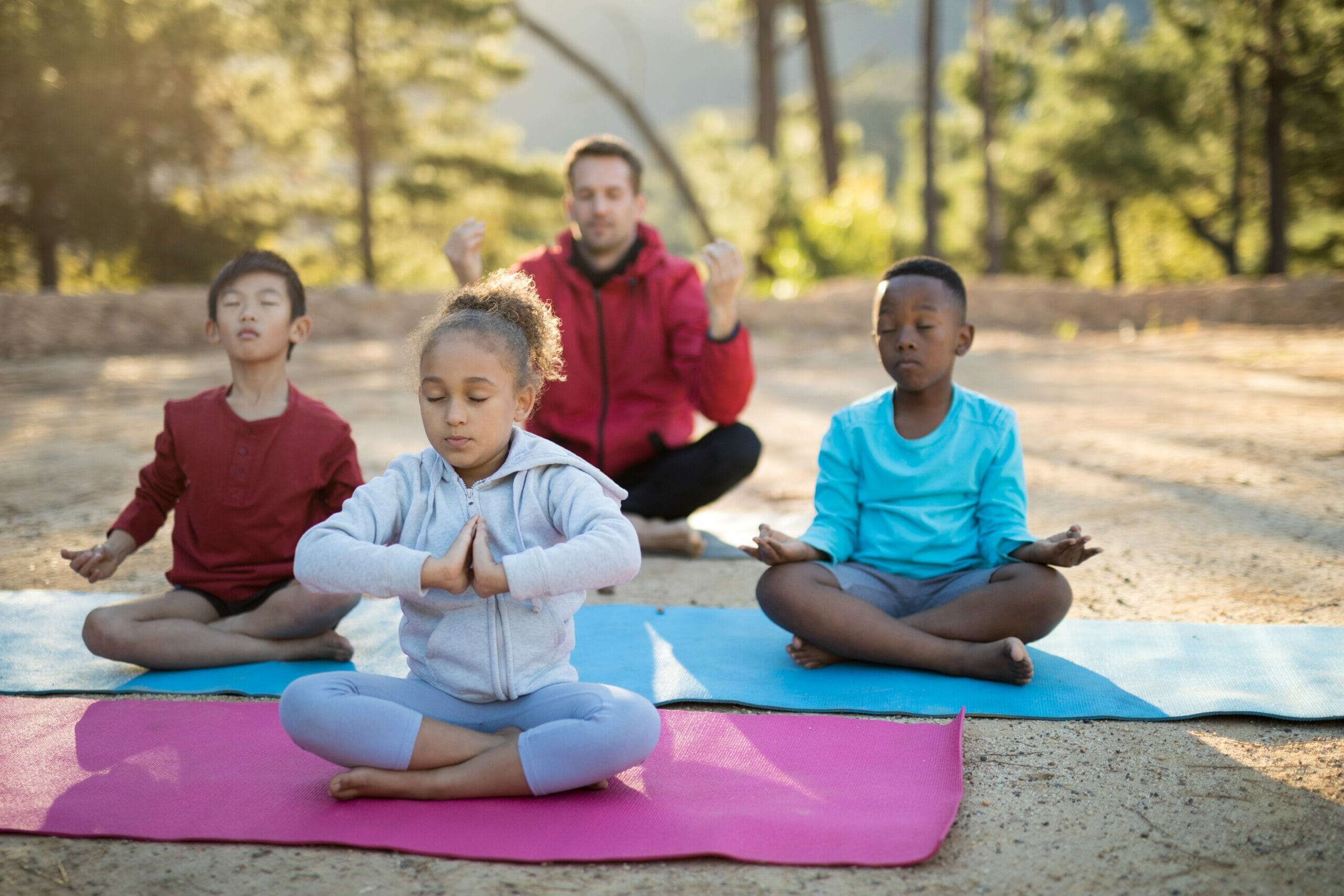 Coach and kids meditating in park